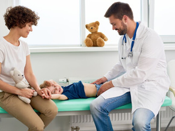 Doctor examinando con sus manos estómago de niño