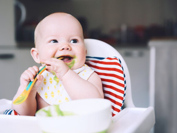 Bebé alegre comiendo con cuchara