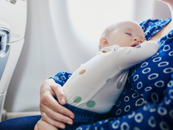 bebé dormido sobre el estómago de su mamá dentro de un avión