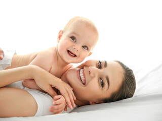 Bebé y mamá sonrientes sobre una cama