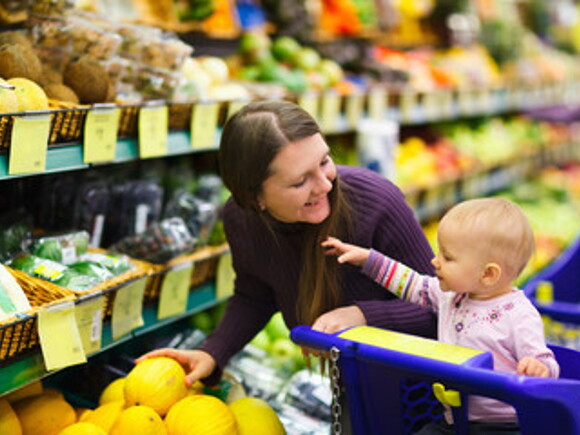 Mamá con su bebé en el supermercado comprando verduras