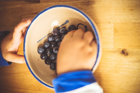 niño comiendo uvas de un recipiente