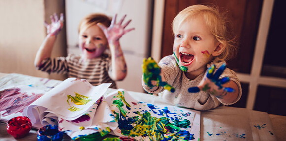 Niños pintando con pintura y riendo.