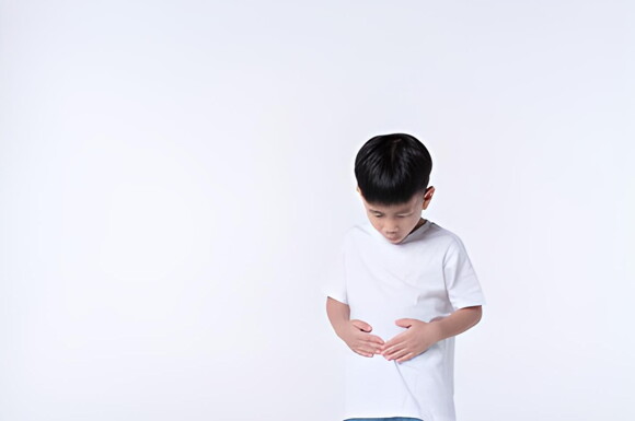Niño tocando su estómago en fondo blanco