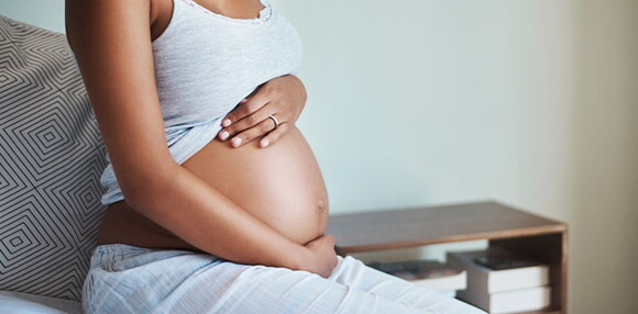 Mujer embarazada sentada tocando el vientre.